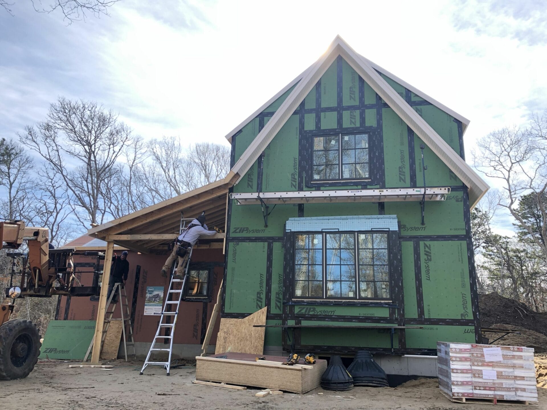 A worker building the front porch of a house.