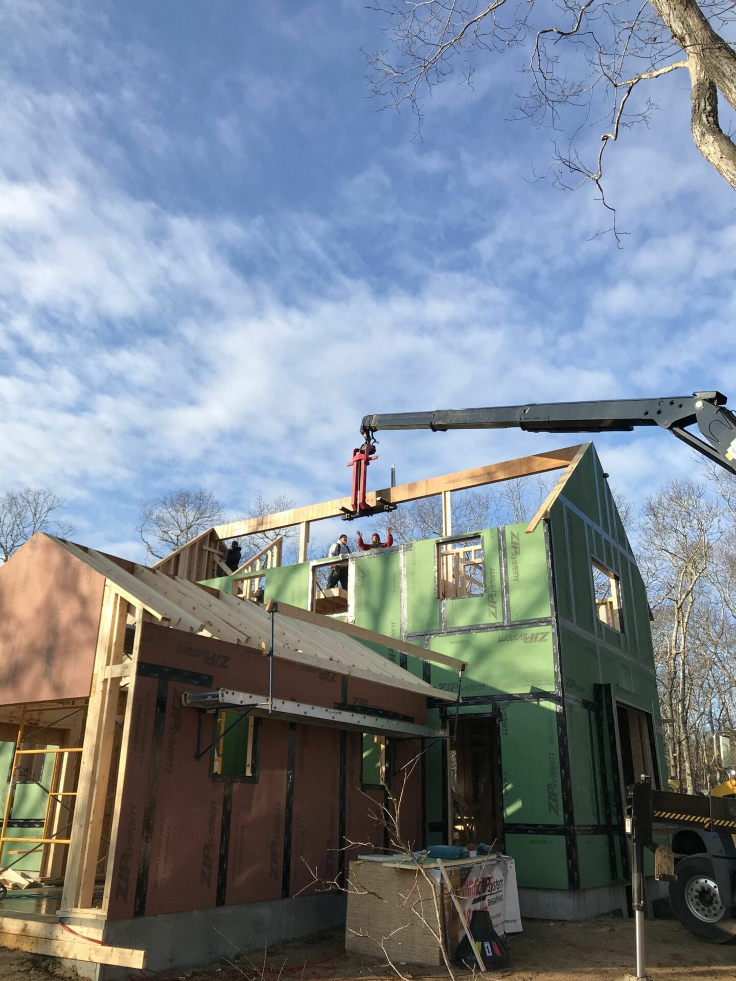 A boom truck lowering the house's main ridge beam into position.