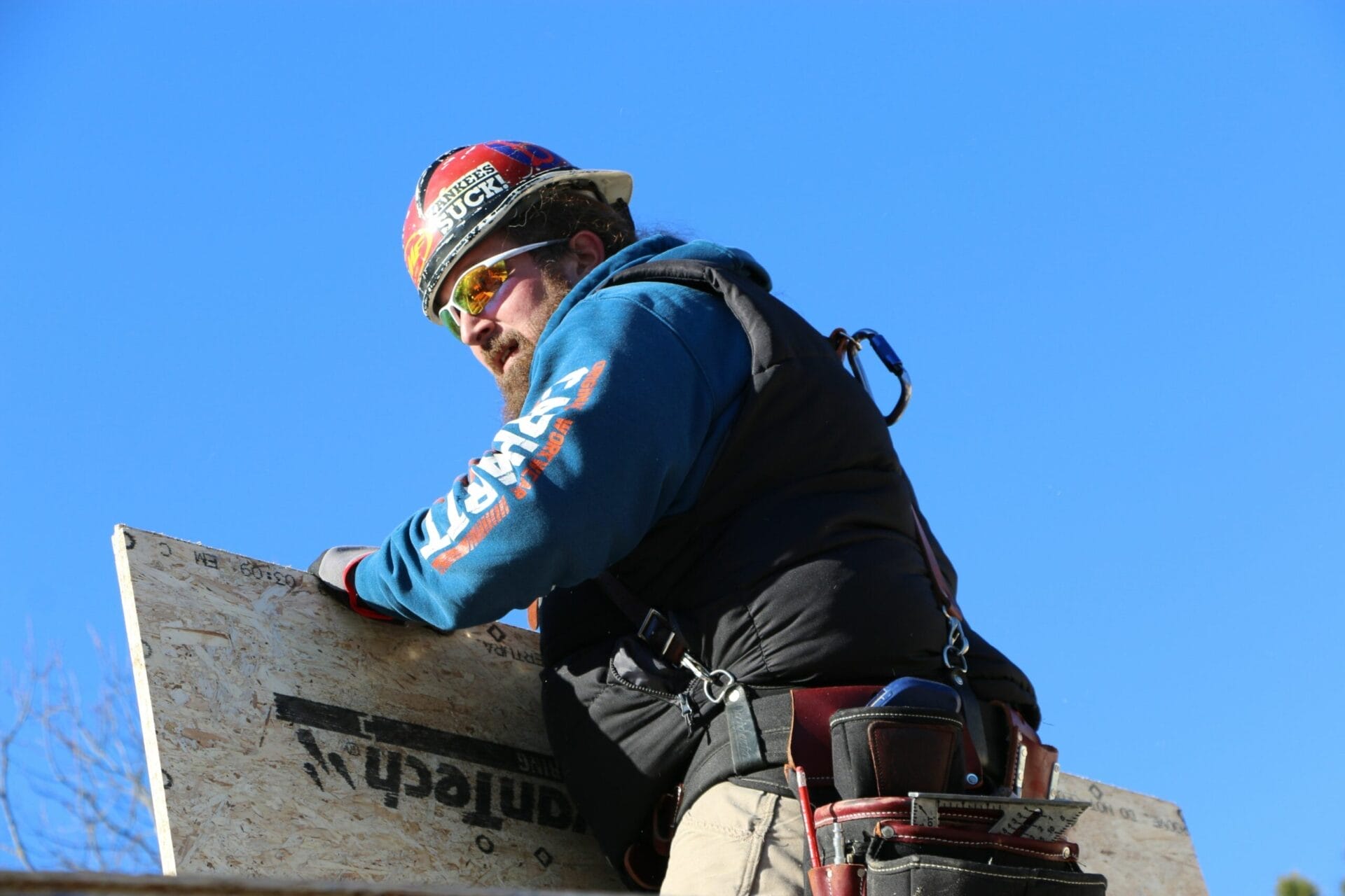 A crew member carries subfloor materials.