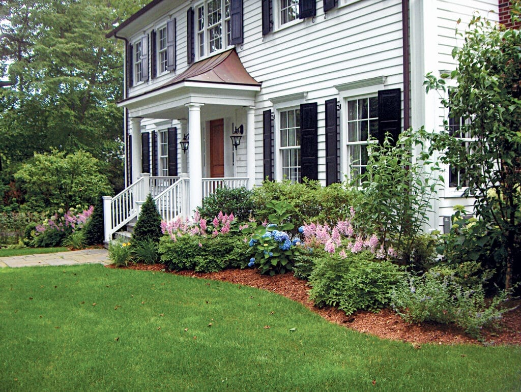 A home with various plants included in it foundation planting.