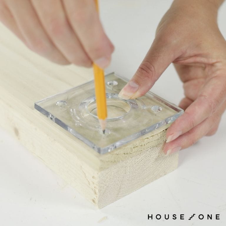 A person traces the footplate onto a board to create a do-it-yourself circle jig.
