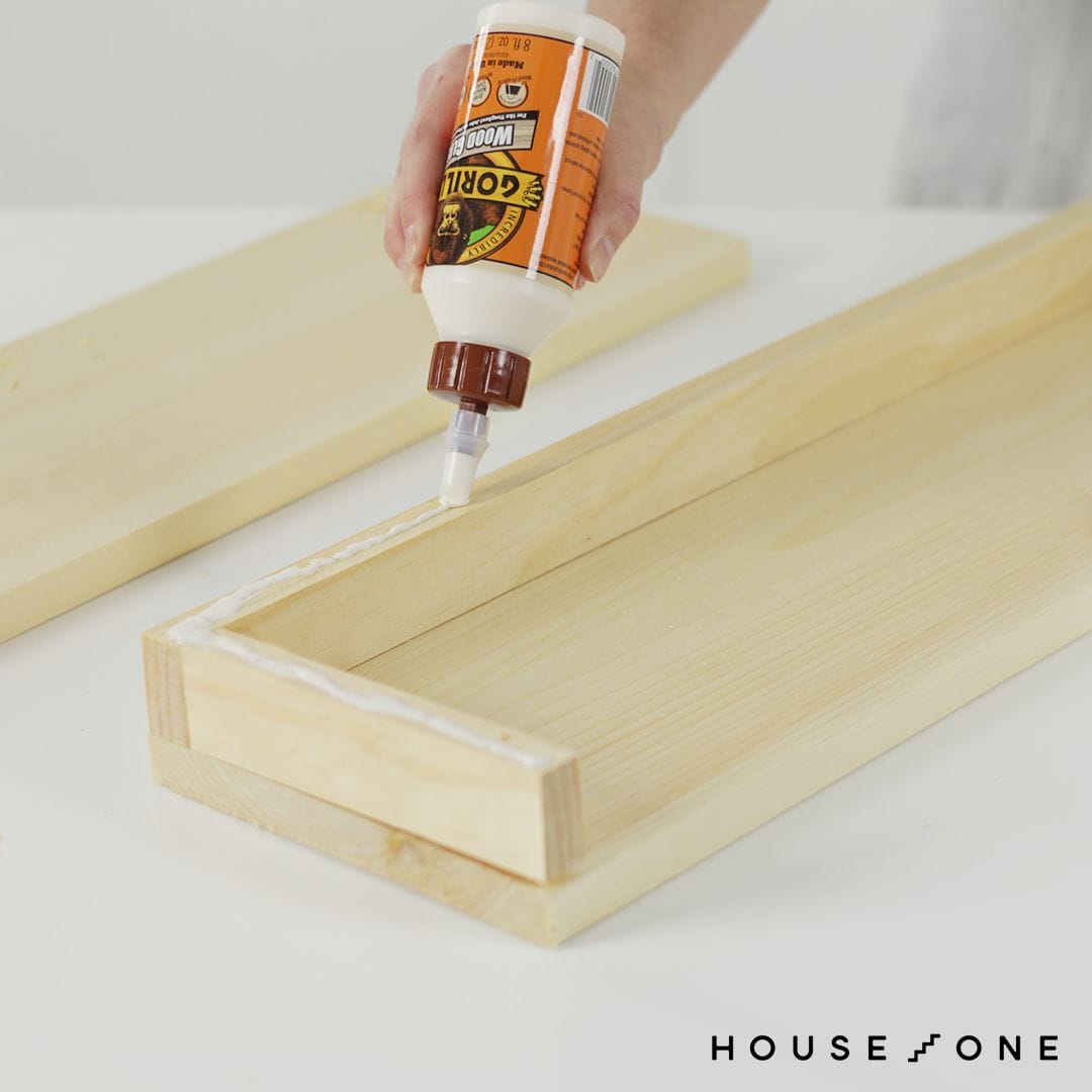 Wood glue is applied to attach the top of the floating shelf.