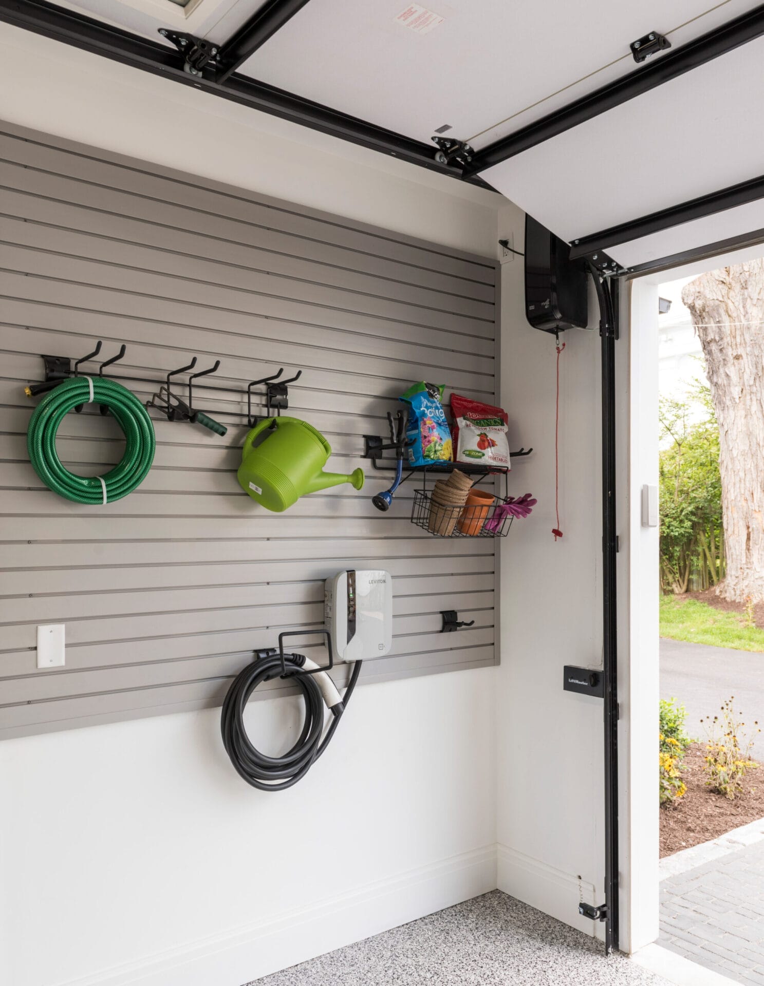 Gardening supplies organized on a track-based system in a garage.