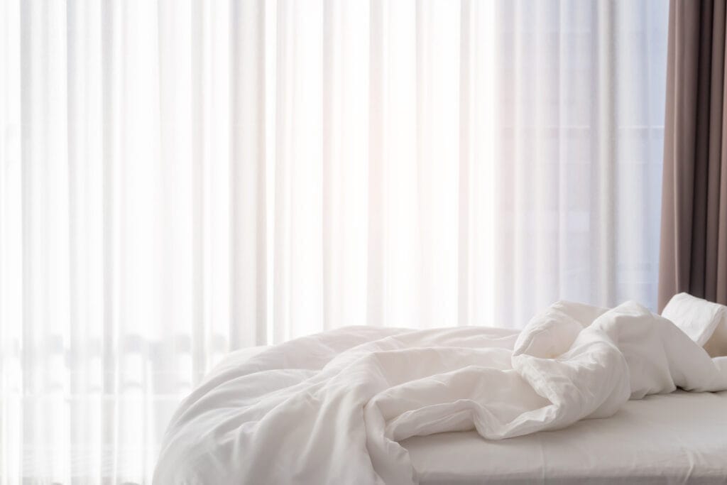 A bedroom with gentle light coming through to aid with sleep.