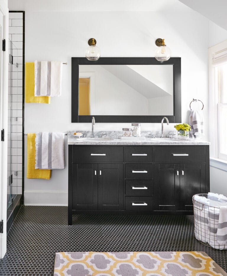 A small bathroom with two sinks with a mirror and two light fixtures above them.