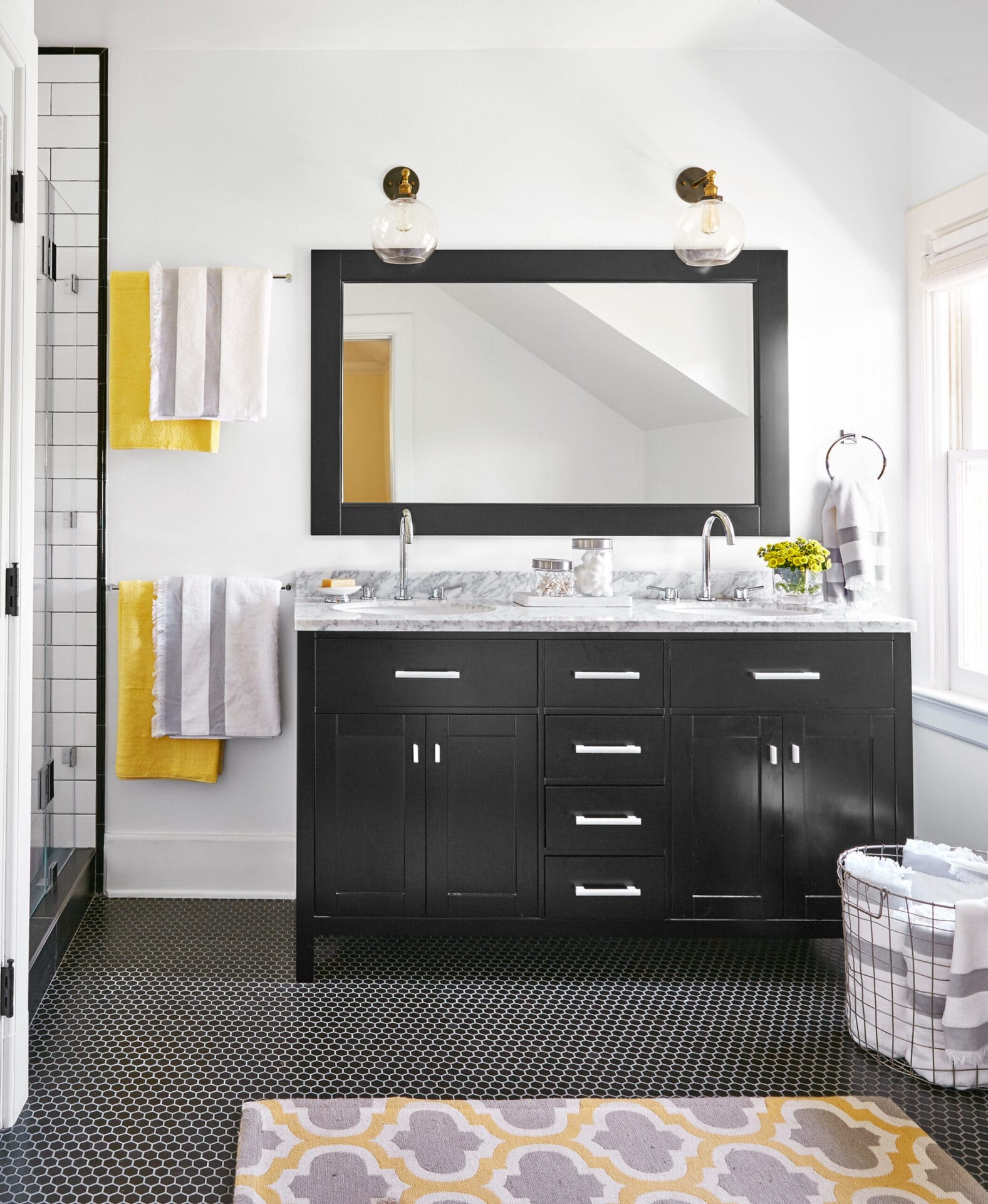 A small bathroom with two sinks with a mirror and two light fixtures above them.