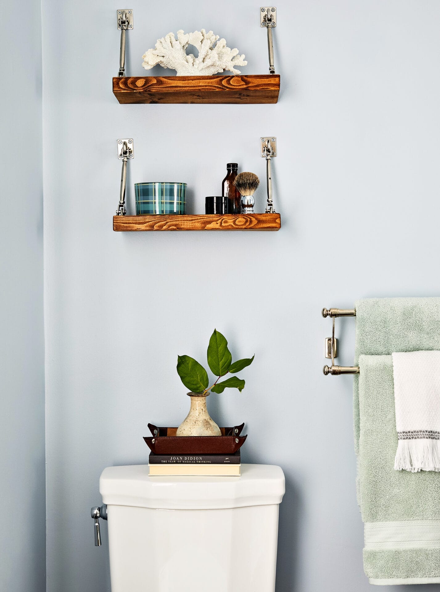A small bathroom with a toilet and 2 hanging shelves.