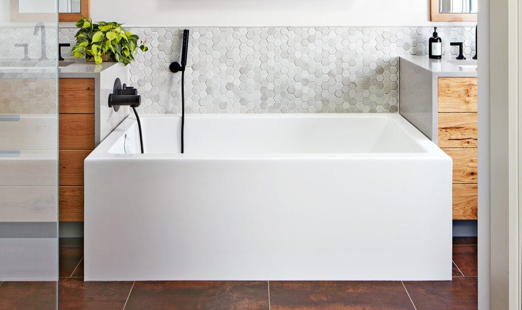 A bathtub with a mat in a small bathroom.
