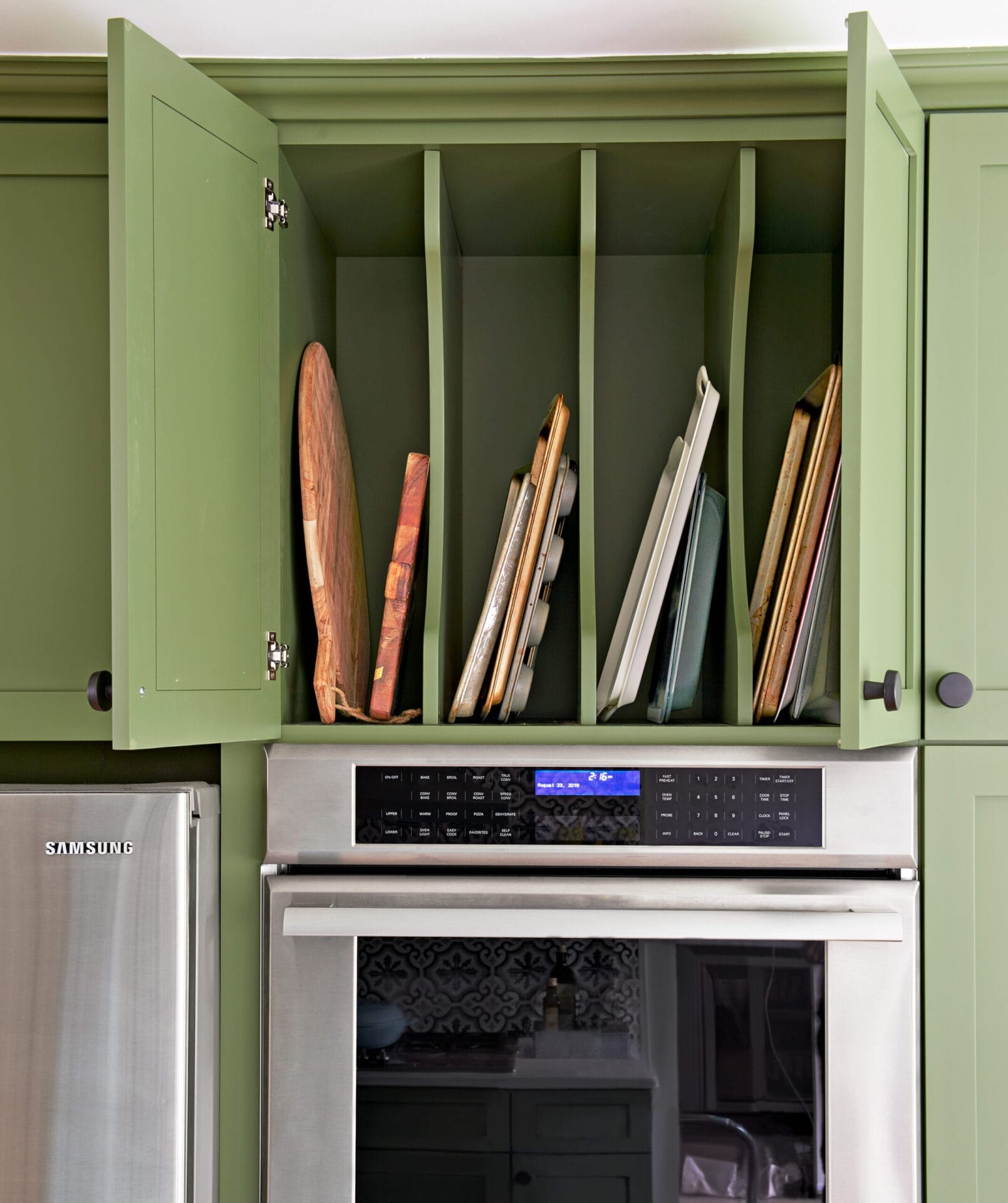 Cabinet storage above double ovens for baking sheets and cutting boards.
