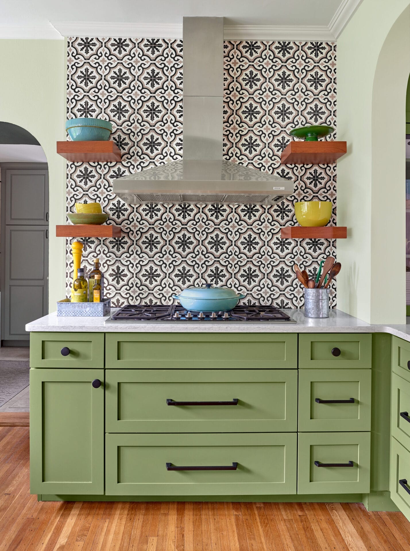 Patterned cement tile backsplash with open shelving flanking chimney-style hood.