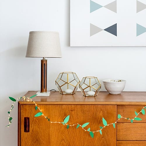 String lighting with paper cutouts in the shape of leaves.