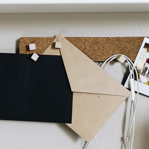 A corkboard being used to hold up various office supplies.