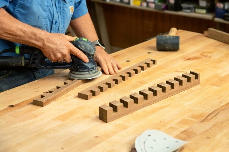 A man notches the crosspieces for a modern platform bench.