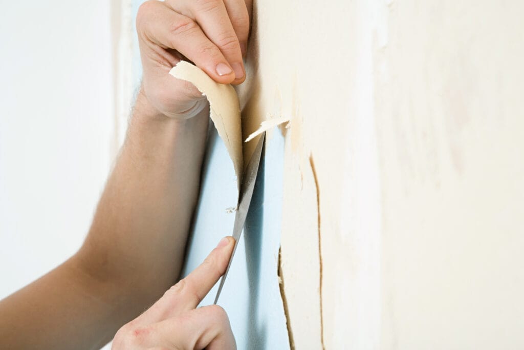 Someone removes wallpaper and wallpaper boarders from the wall.