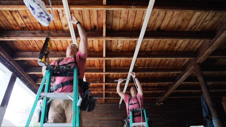 Two men using a DeWalt Cordless Cable Stapler to apply staples to a cable.