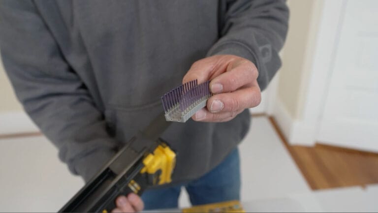 A man showing the staples that are loaded into a DeWalt Cordless Cable Stapler.