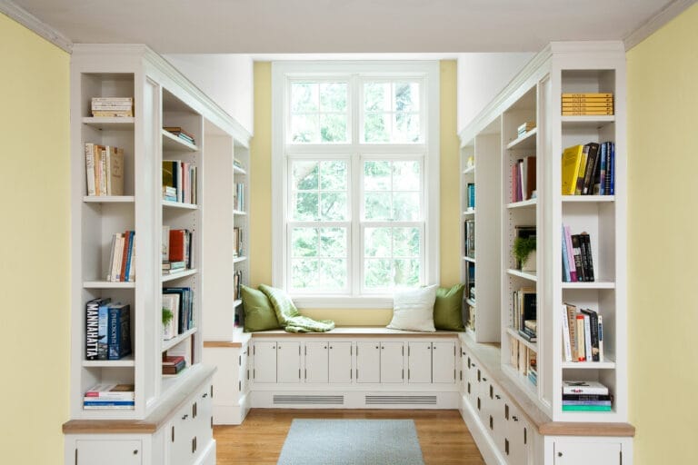 A nook with a seat by the window and a home library on either side.