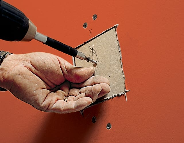 A patch is screwed into the wall where a drywall hole once was.
