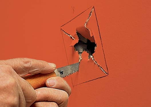 A hole in drywall is prepped to be patched.