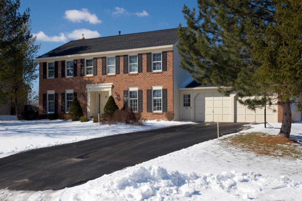 Snowy house with a driveway kept clear by a heated driveway system.