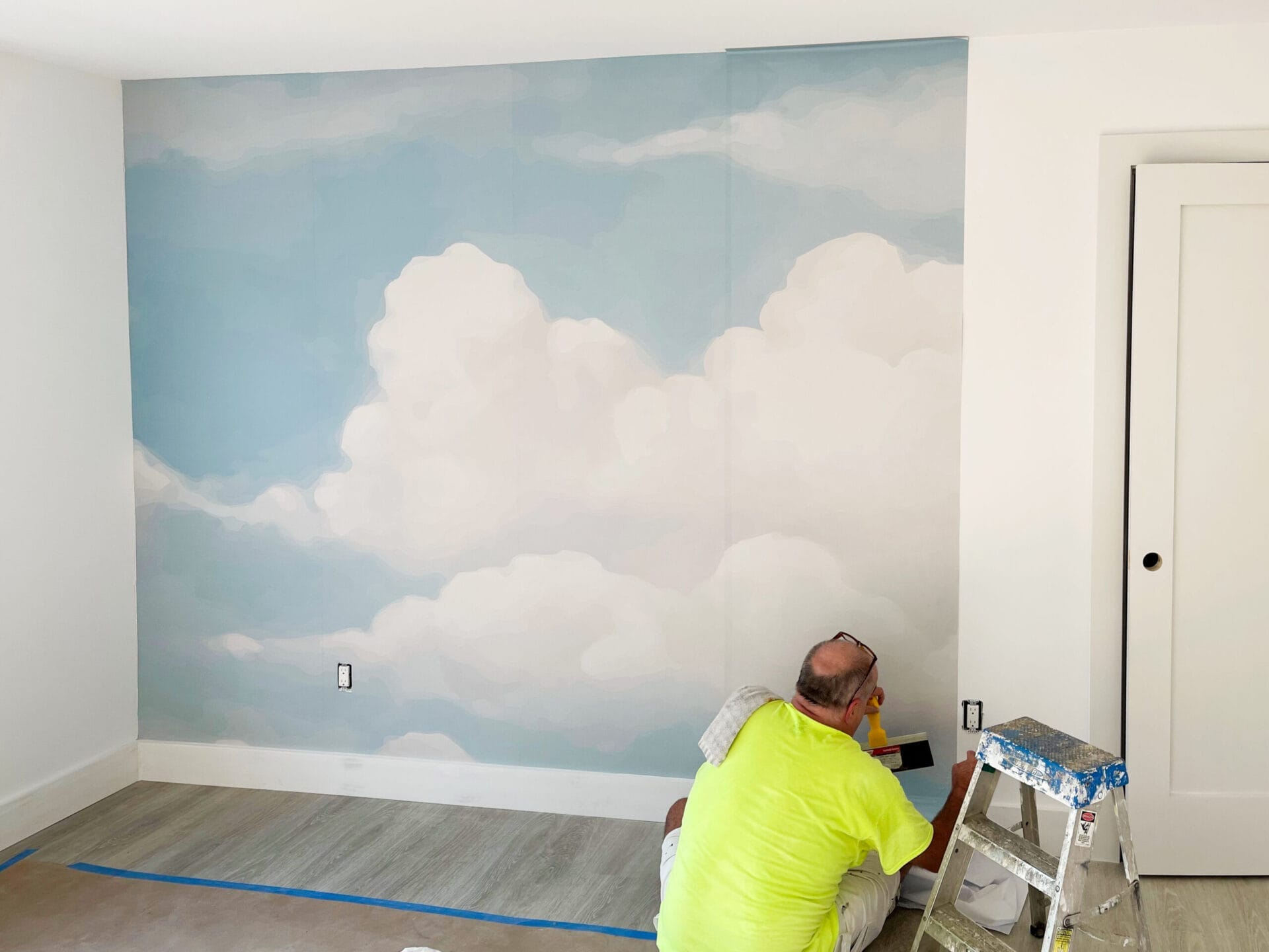 Peel-and-stick cloud wallpaper installation in nursery.