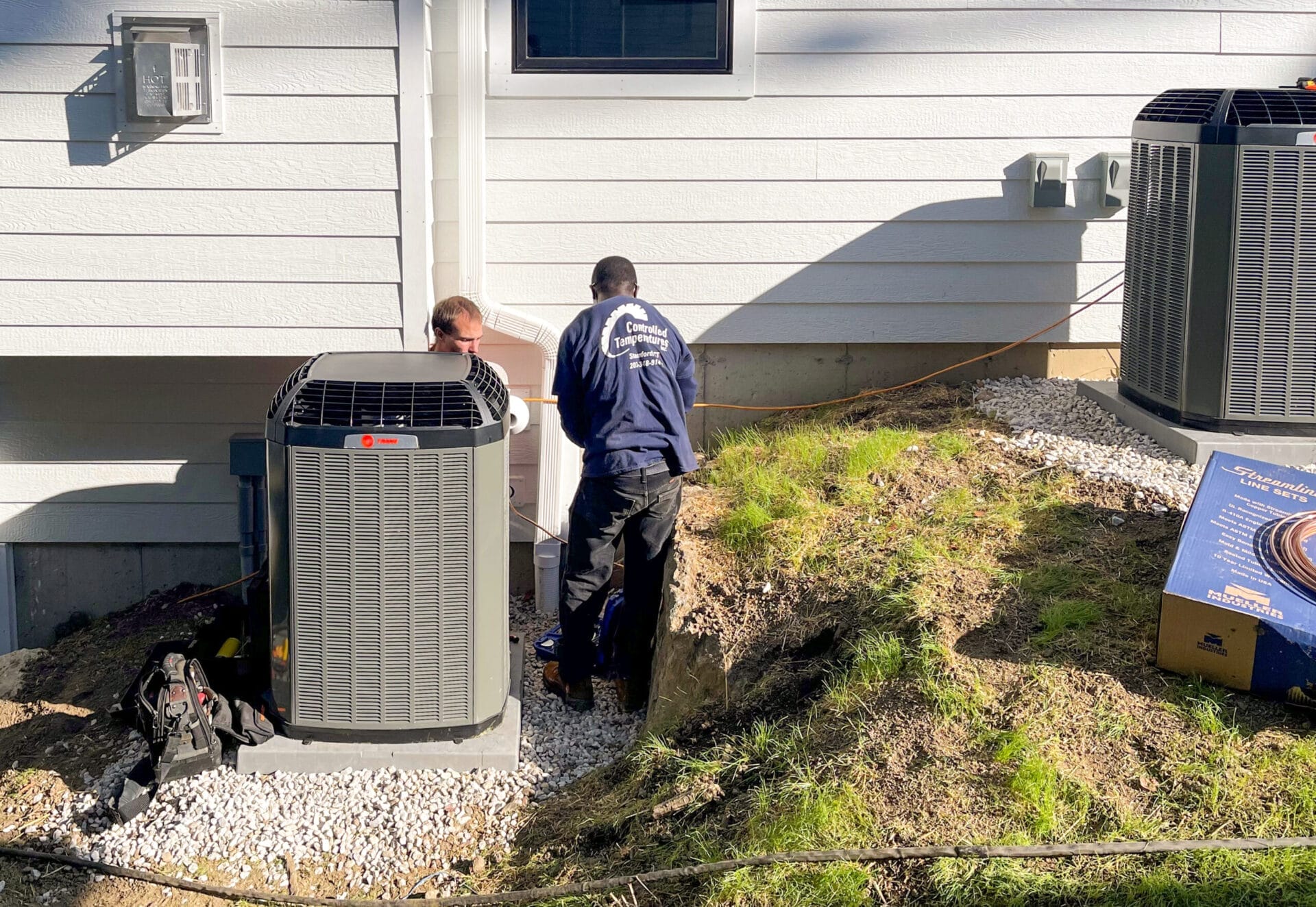 Men work on Trane air conditioning compressors.