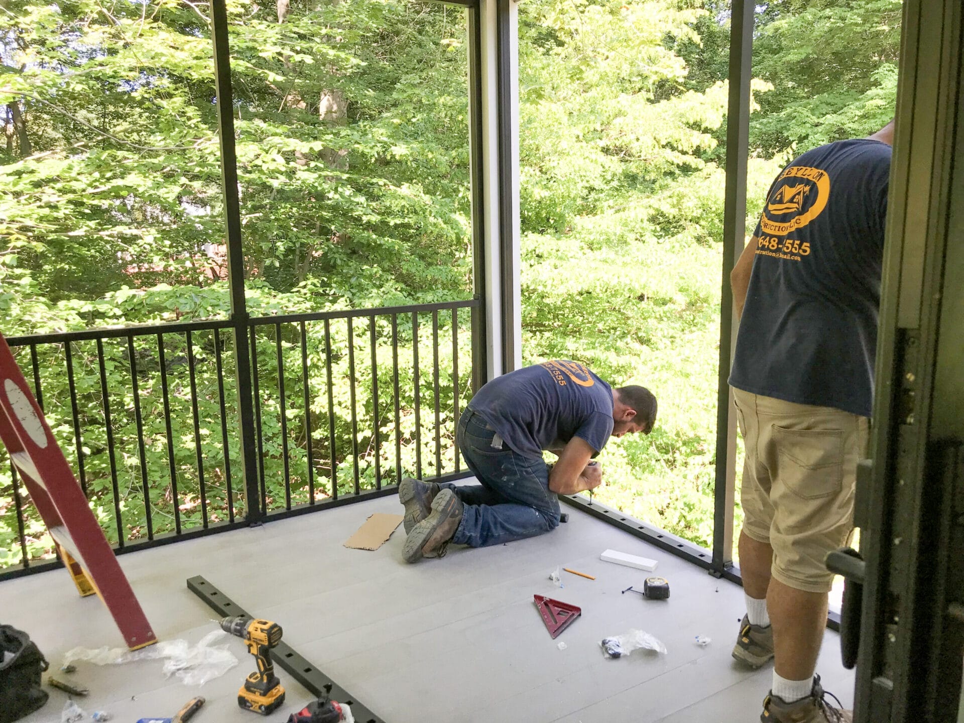 Carpenters installing aluminum railings on second-story screened porch.