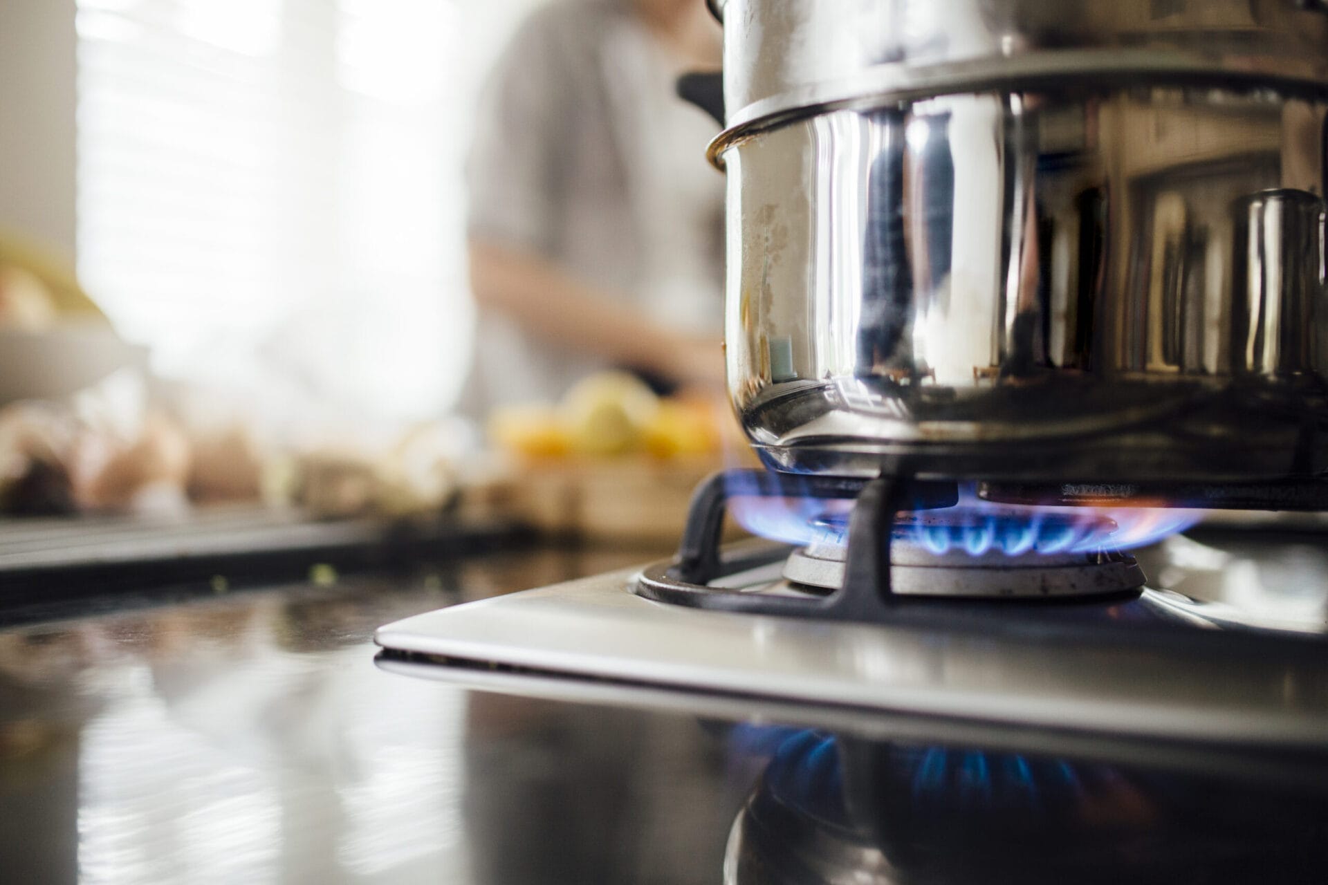 A stainless steel pot over a lit stove burner.