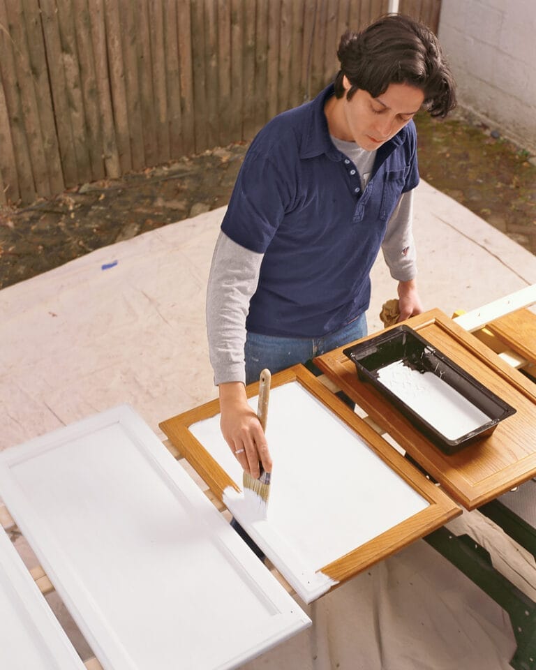 A man primes kitchen cabinets.