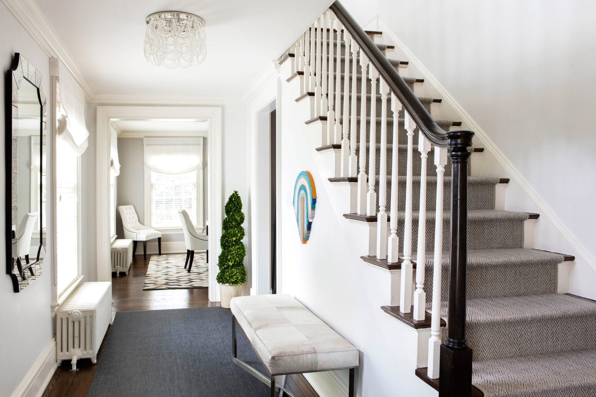 A staircase made grand with  thin, painted balusters and blocky mahogany newels.