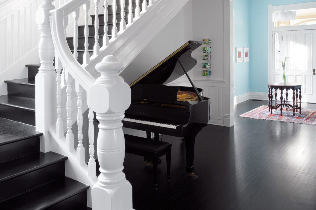 A grand staircase with elaborate details and a grand piano.