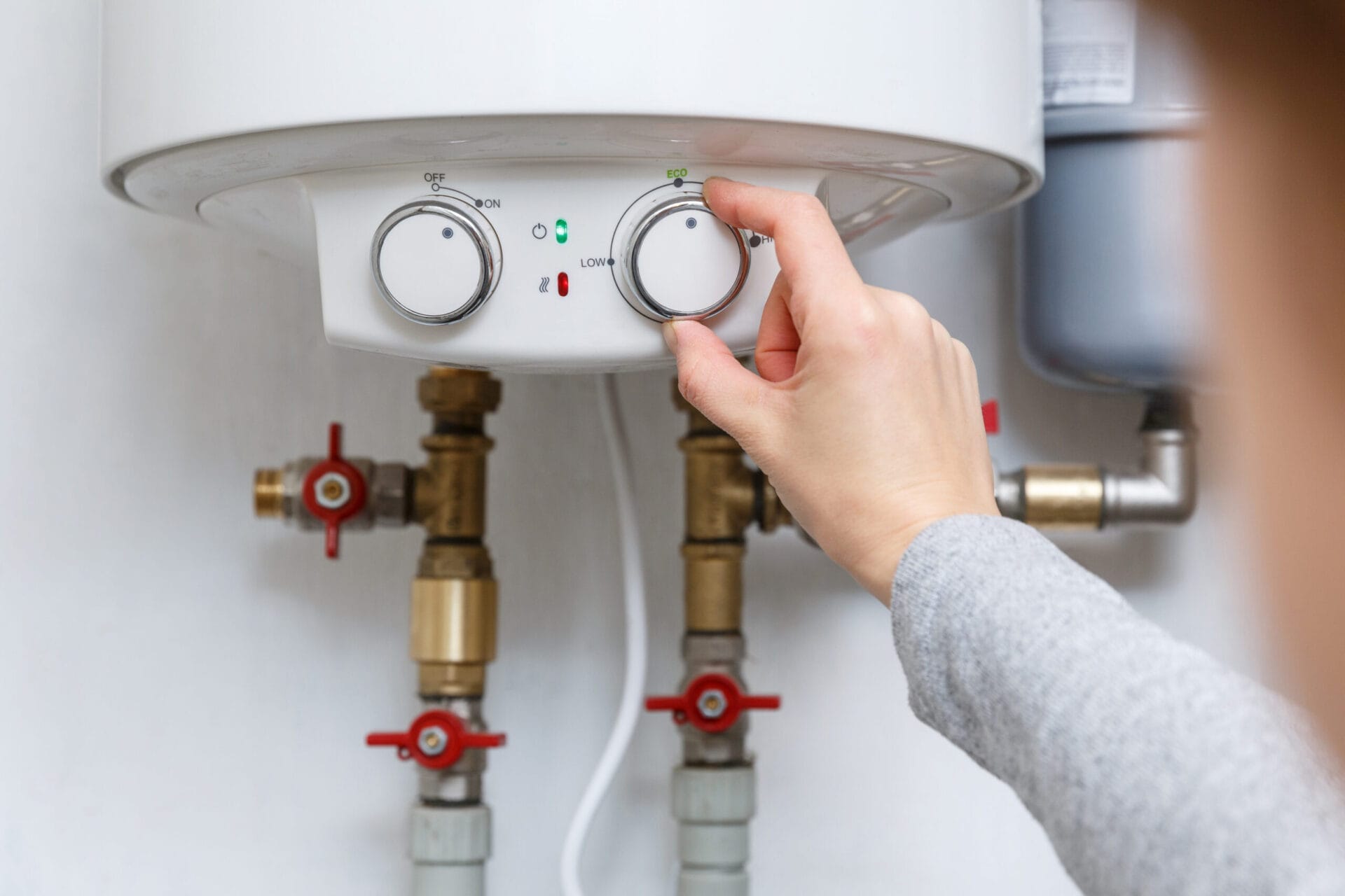 A person setting the thermostat settings for a water heater.