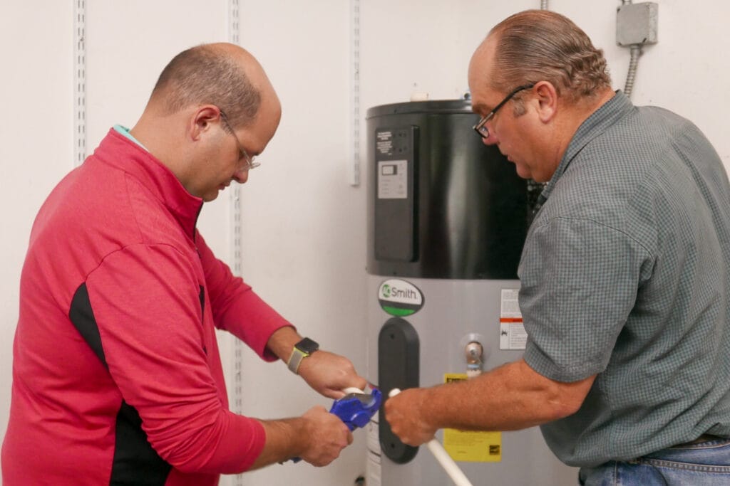 Two professionals plumbers installing a heat pump water heater