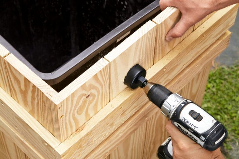 A kit-supplied hole saw is used to cut through the barrel and bin of the rain barrel.