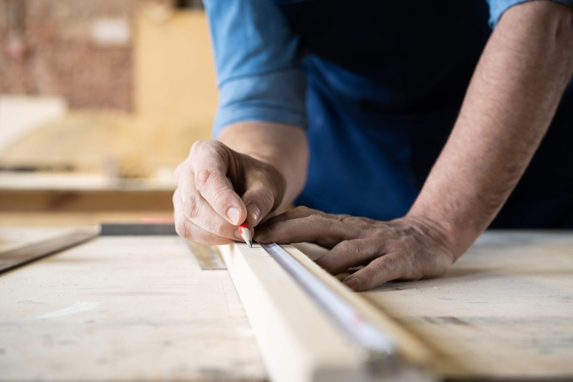 Man making pencil markings on a piece of trim.