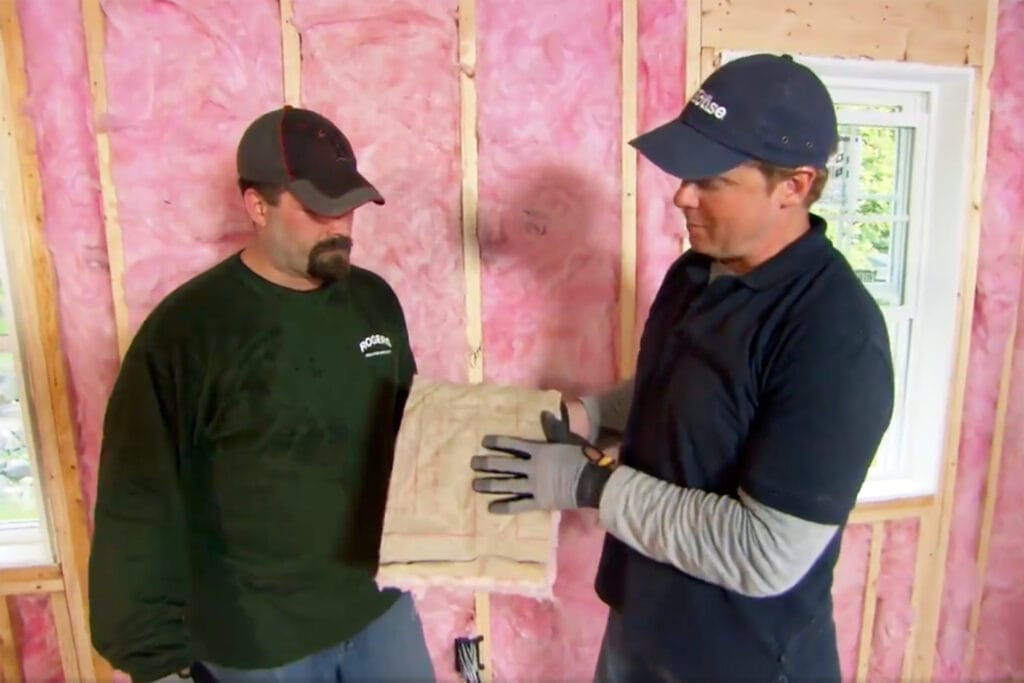 Two men installing fiberglass insulation