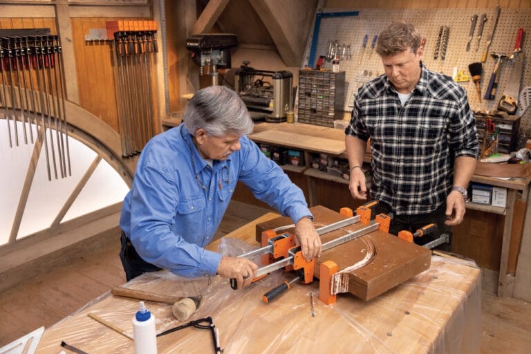 A clamp being applied to the base of a demilune table.