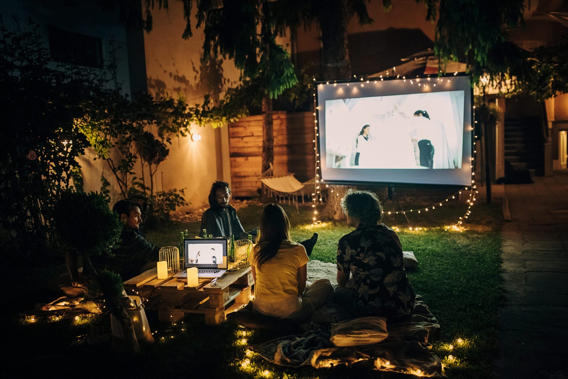 Friends watching a movie on the video projector in their backyard movie theater.
